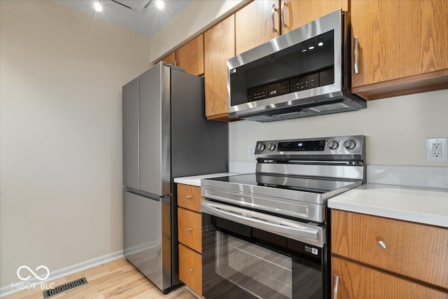 kitchen featuring appliances with stainless steel finishes and light hardwood / wood-style flooring