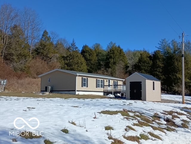 view of front facade featuring central AC, a deck, and a storage shed