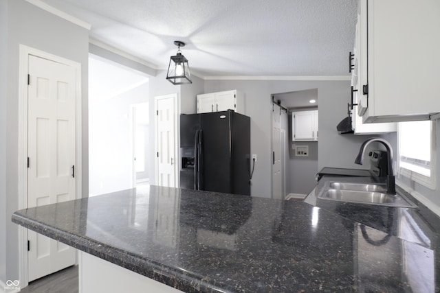 kitchen with sink, black fridge, white cabinets, a barn door, and kitchen peninsula