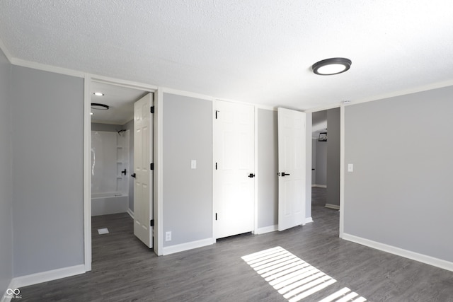 unfurnished bedroom with dark wood-type flooring, a textured ceiling, and ensuite bathroom