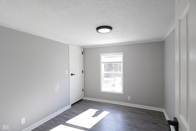 empty room with dark wood-type flooring, ornamental molding, and a textured ceiling