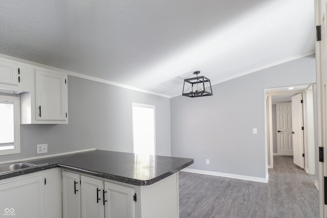 kitchen with white cabinetry, ornamental molding, kitchen peninsula, and light hardwood / wood-style floors