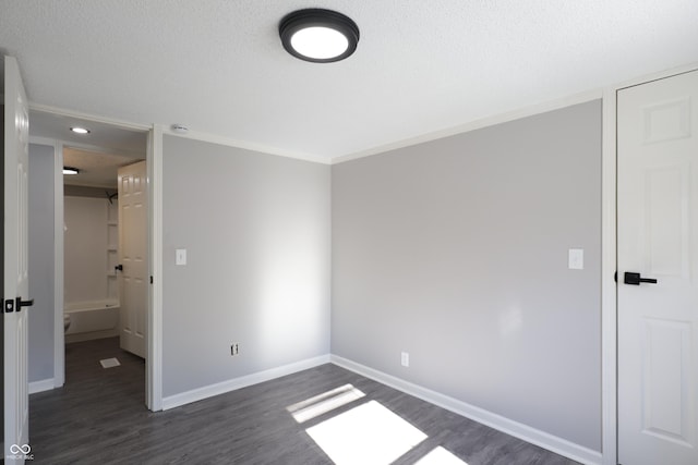 unfurnished bedroom with crown molding, dark wood-type flooring, and a textured ceiling