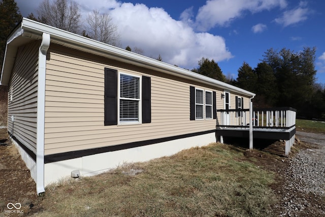 view of side of property featuring a deck and a lawn