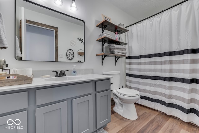 bathroom featuring vanity, a textured ceiling, wood-type flooring, and toilet