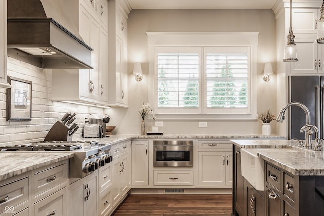 kitchen with premium range hood, white cabinetry, appliances with stainless steel finishes, and light stone counters