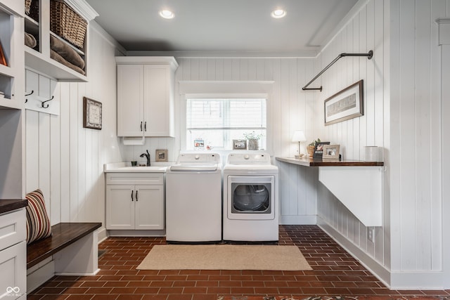 washroom with sink, washing machine and dryer, and cabinets