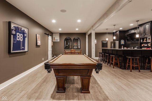 game room with pool table, bar area, a barn door, and light hardwood / wood-style floors