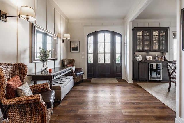 foyer entrance featuring dark wood-type flooring, bar, and beverage cooler