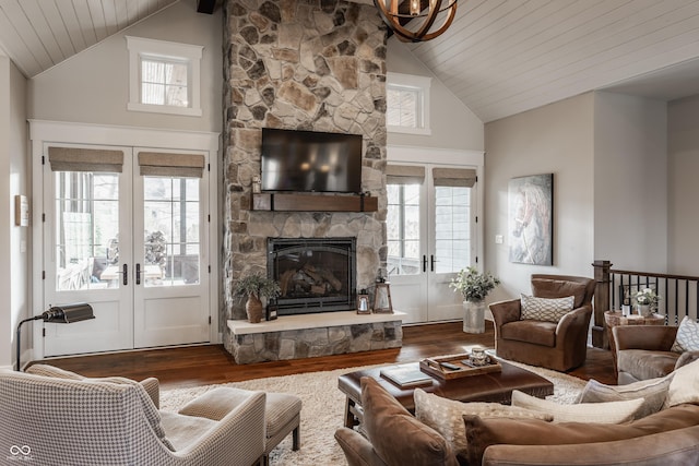 living room with french doors, high vaulted ceiling, a stone fireplace, and hardwood / wood-style floors