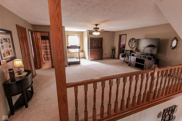 living room with ceiling fan, light colored carpet, and a textured ceiling