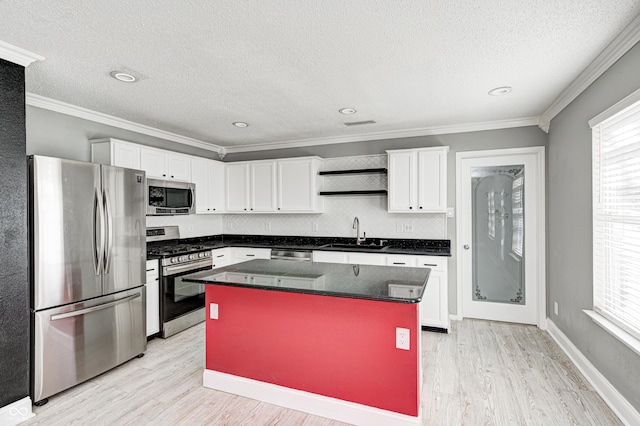 kitchen featuring sink, crown molding, appliances with stainless steel finishes, white cabinetry, and a center island