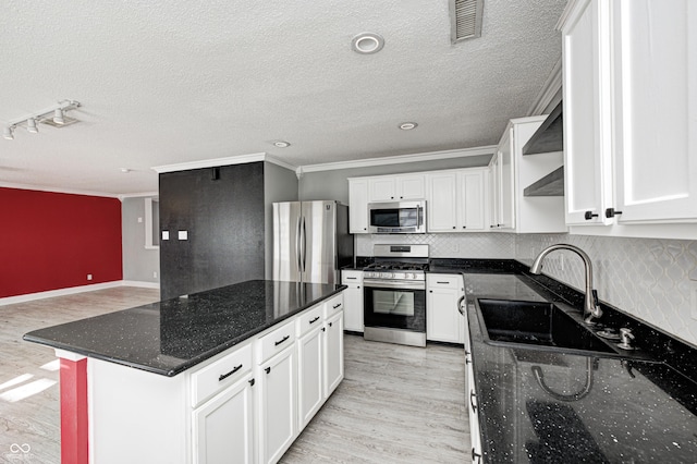 kitchen featuring sink, dark stone countertops, light wood-type flooring, stainless steel appliances, and white cabinets