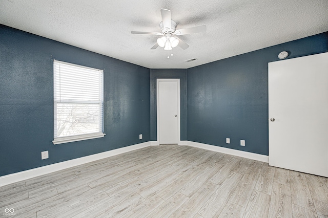 spare room featuring ceiling fan, light hardwood / wood-style flooring, and a textured ceiling