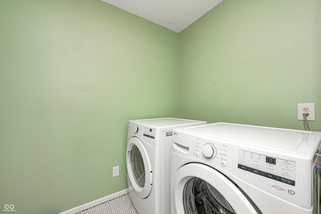 laundry area with tile patterned floors, washing machine and dryer, and a textured ceiling