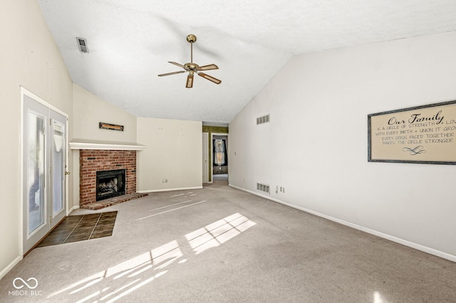 unfurnished living room featuring lofted ceiling, a textured ceiling, ceiling fan, a fireplace, and carpet