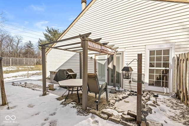 snow covered patio with area for grilling and a pergola