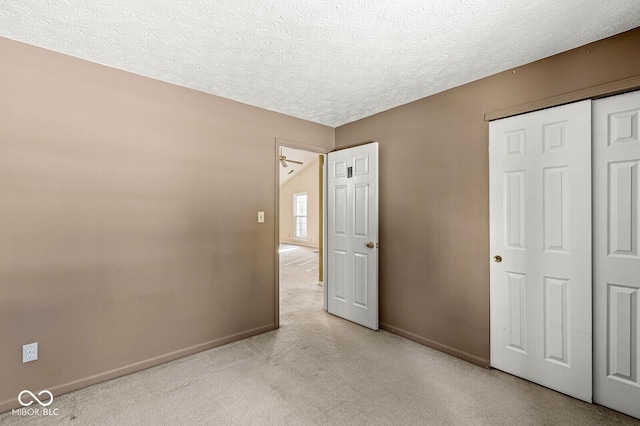 unfurnished bedroom with light carpet, a closet, and a textured ceiling