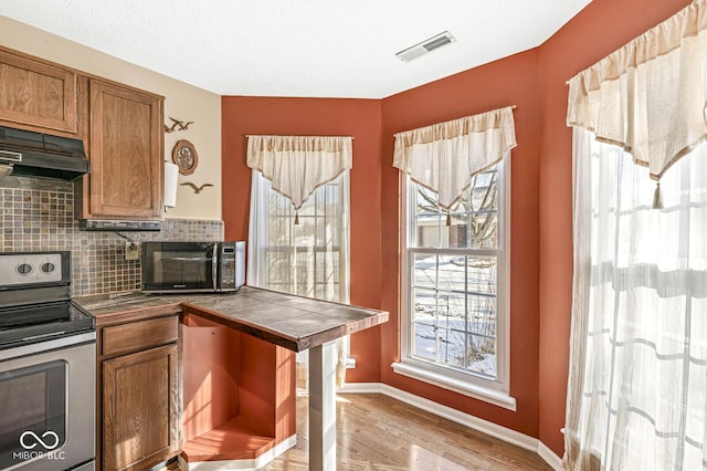 kitchen featuring decorative backsplash, light hardwood / wood-style flooring, tile countertops, and stainless steel electric range oven