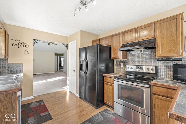 kitchen with sink, light hardwood / wood-style flooring, backsplash, tile counters, and black appliances