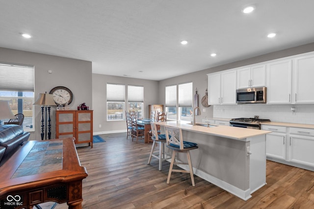 kitchen featuring sink, a breakfast bar area, white cabinetry, appliances with stainless steel finishes, and an island with sink