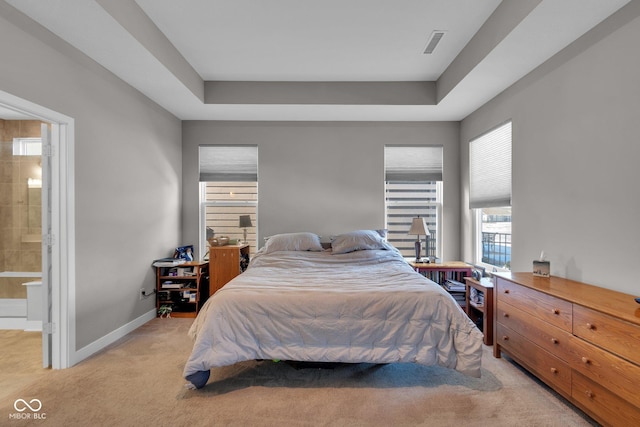 carpeted bedroom with a raised ceiling and ensuite bathroom