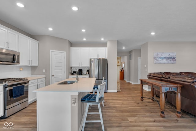 kitchen with sink, appliances with stainless steel finishes, an island with sink, white cabinets, and decorative backsplash