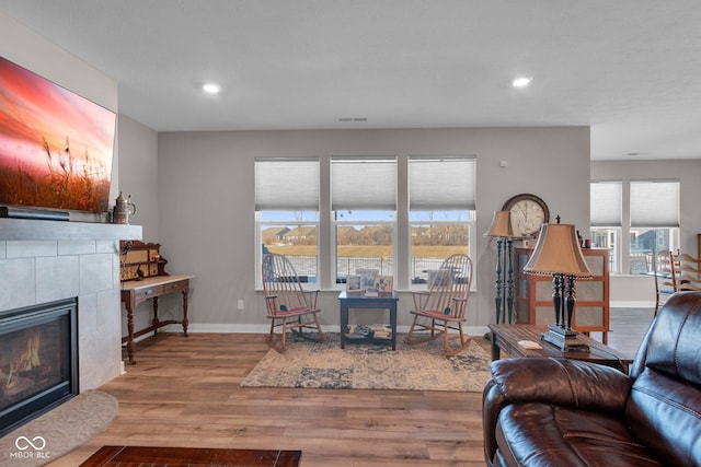 living room featuring a tile fireplace and light wood-type flooring