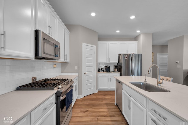 kitchen featuring stainless steel appliances, sink, light hardwood / wood-style flooring, and white cabinets