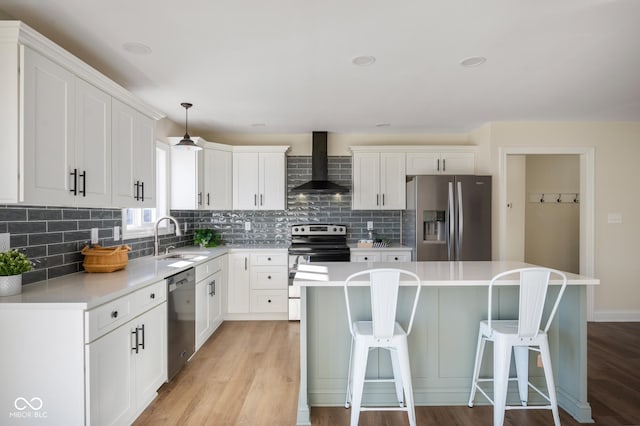 kitchen with wall chimney range hood, stainless steel appliances, sink, and a center island