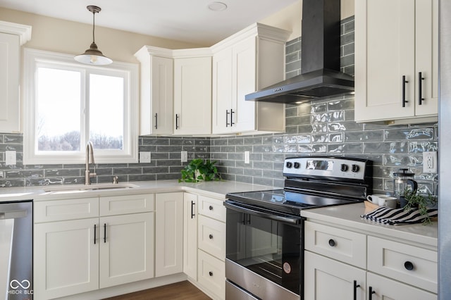 kitchen with appliances with stainless steel finishes, decorative light fixtures, sink, white cabinets, and wall chimney range hood