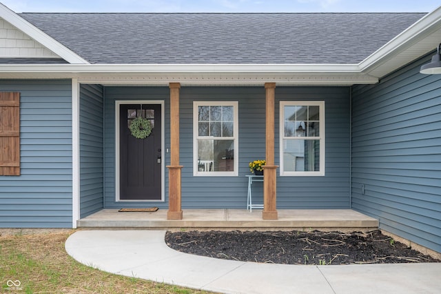doorway to property with a shingled roof and covered porch
