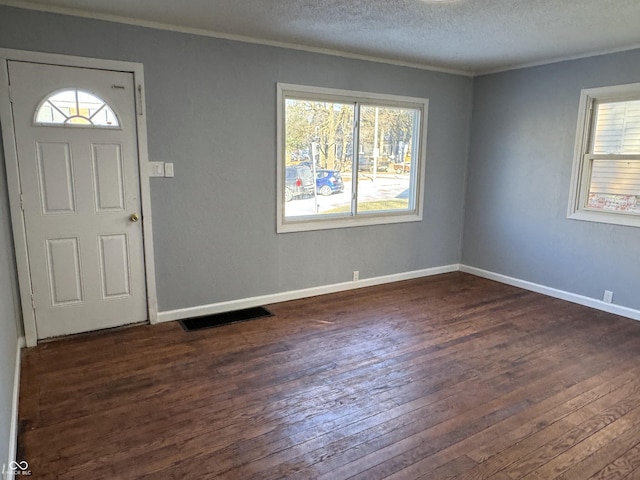 entryway featuring dark hardwood / wood-style flooring, ornamental molding, and a textured ceiling