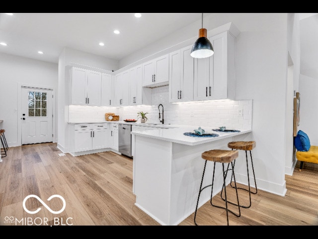 kitchen featuring white cabinetry, a breakfast bar area, dishwasher, and hanging light fixtures