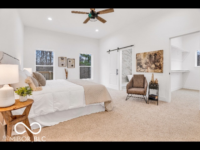 bedroom with a barn door, light colored carpet, and ceiling fan