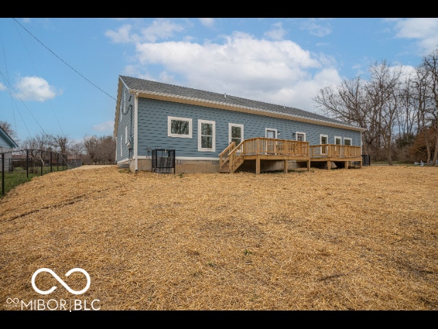 rear view of property with a wooden deck and a lawn