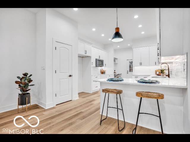 kitchen with white cabinetry, sink, backsplash, and kitchen peninsula