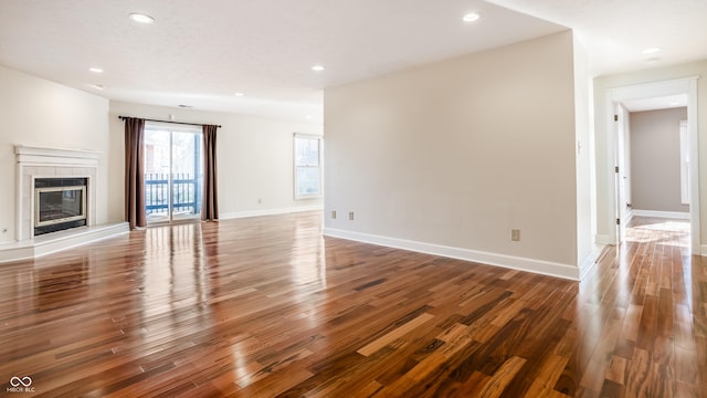 unfurnished living room with a tiled fireplace and hardwood / wood-style floors