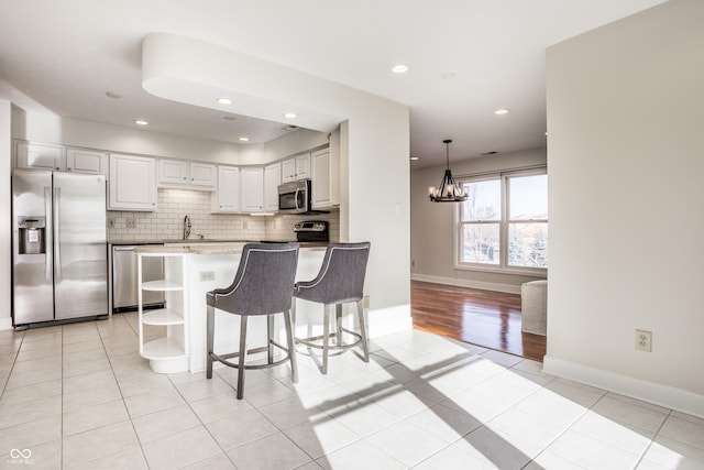 kitchen featuring white cabinetry, light tile patterned floors, stainless steel appliances, light stone countertops, and backsplash