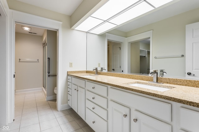 bathroom featuring a shower with door, vanity, tile patterned floors, and a skylight