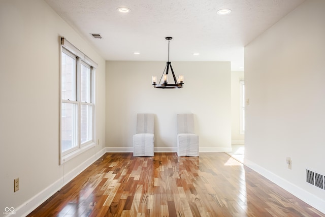 unfurnished room featuring hardwood / wood-style floors, a textured ceiling, and a chandelier