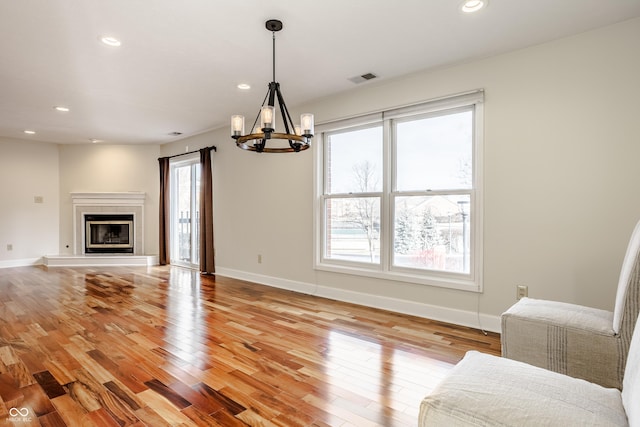 unfurnished living room featuring an inviting chandelier and light hardwood / wood-style flooring