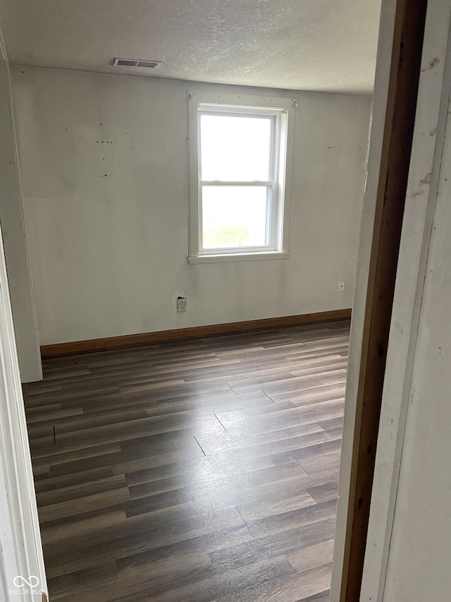 spare room featuring hardwood / wood-style floors and a textured ceiling