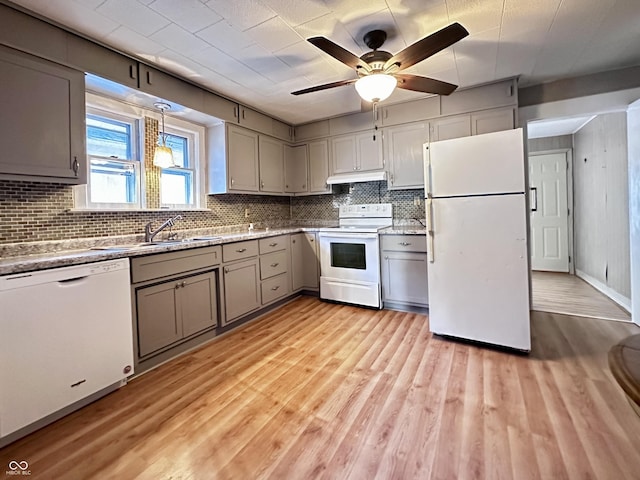 kitchen featuring pendant lighting, sink, white appliances, backsplash, and light hardwood / wood-style floors