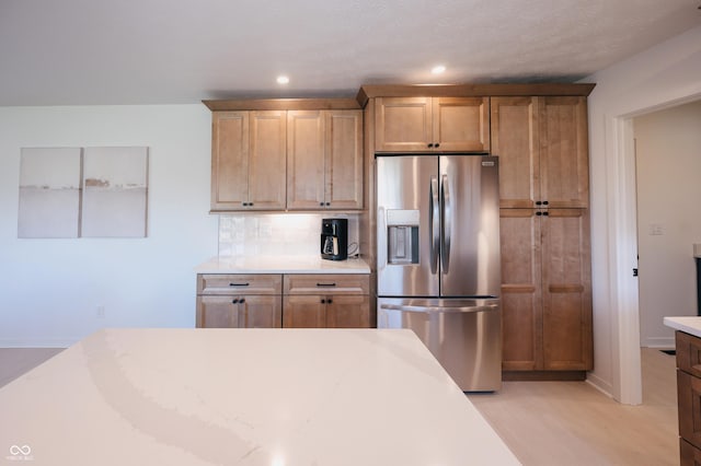 kitchen featuring light hardwood / wood-style flooring, backsplash, and stainless steel fridge with ice dispenser