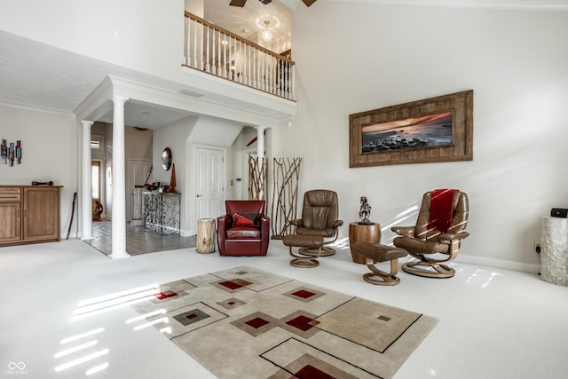 living area featuring crown molding, ceiling fan, carpet flooring, and ornate columns