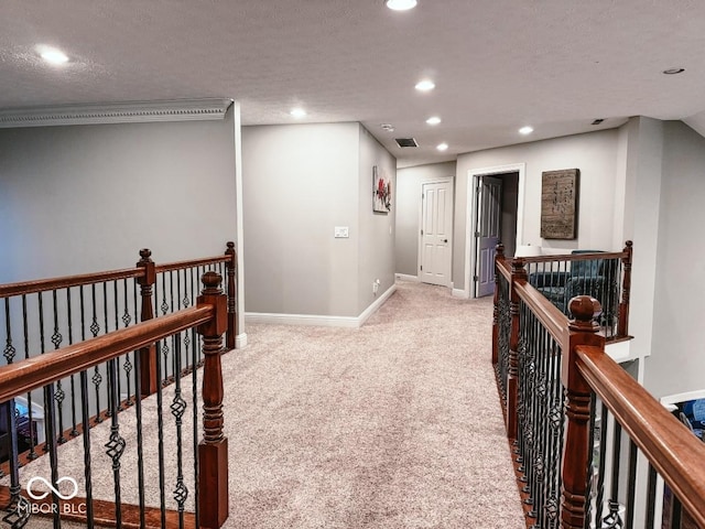 hall featuring light colored carpet, ornamental molding, and a textured ceiling