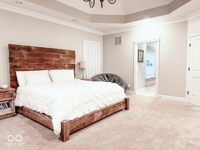 bedroom featuring crown molding, ensuite bath, a tray ceiling, and light carpet