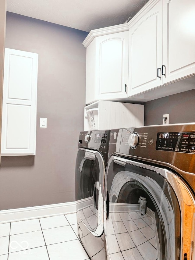 laundry room featuring cabinets, light tile patterned flooring, and washer and dryer