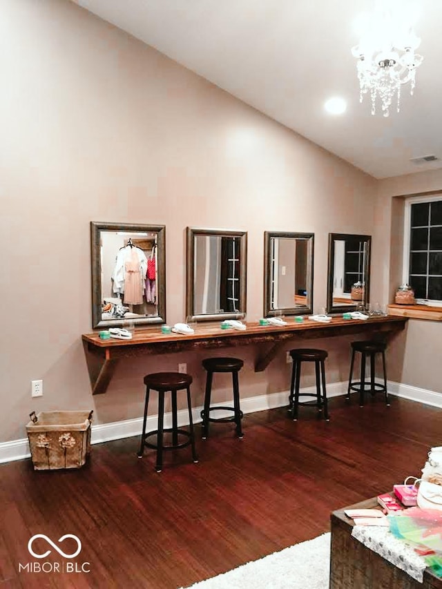 kitchen featuring wood-type flooring, vaulted ceiling, a chandelier, and a kitchen breakfast bar